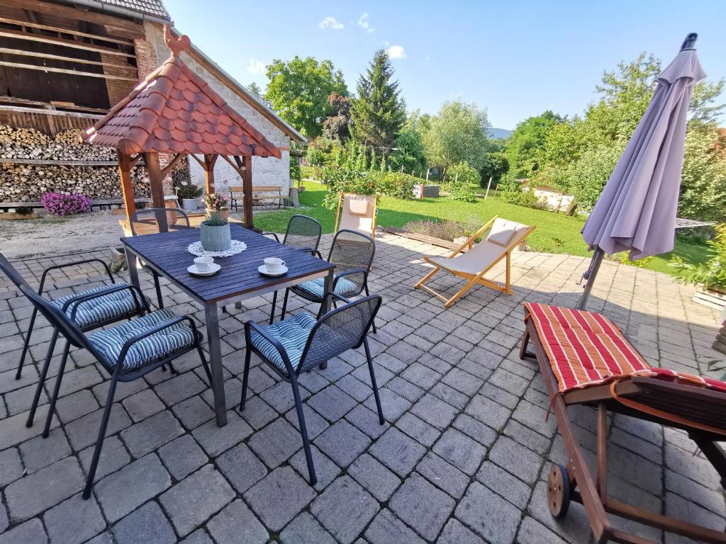 un patio con mesa, sillas y sombrilla en Charming village house with patio and garden, en Slovenske Konjice