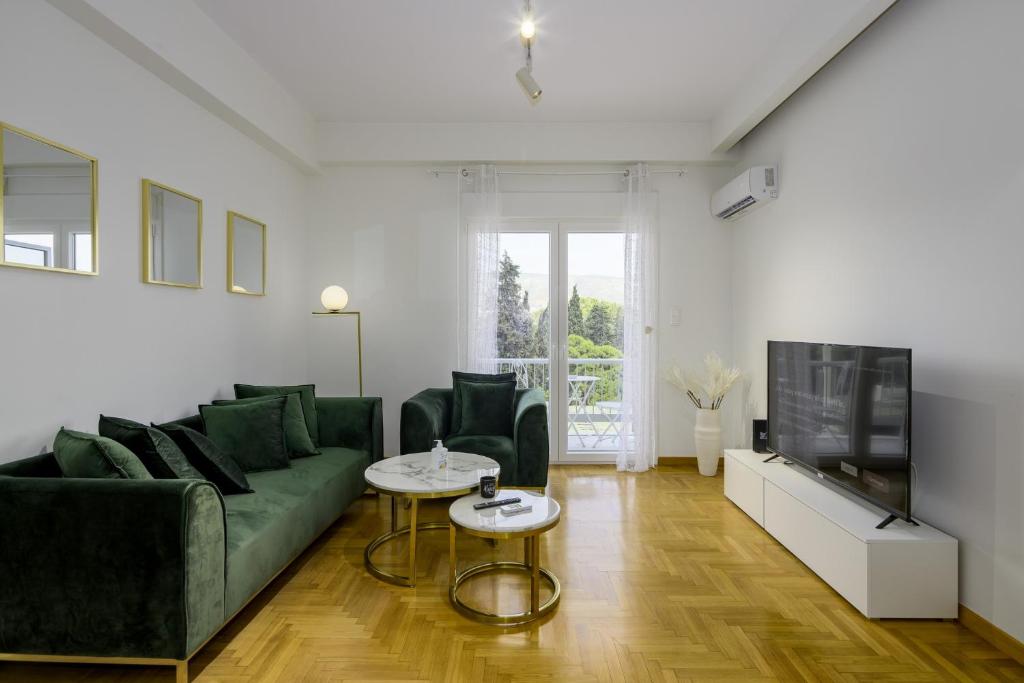 ein Wohnzimmer mit einem grünen Sofa und einem TV in der Unterkunft Lush Emerald apt in the heart of Athens! in Athen