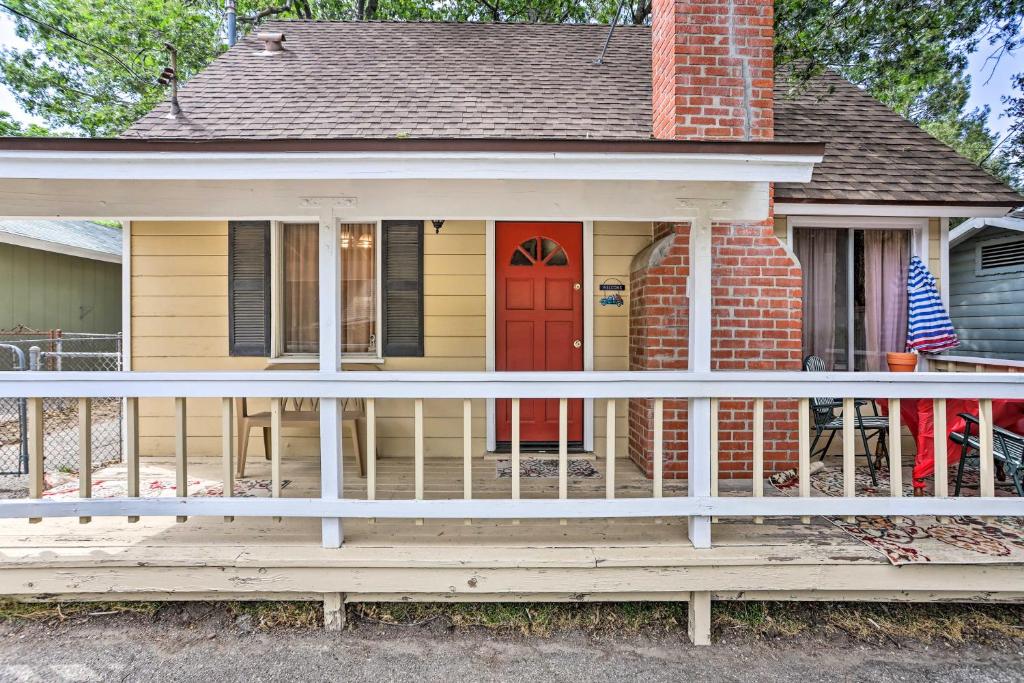 une maison avec une terrasse couverte en bois et une porte rouge dans l'établissement Cozy Crestline Cabin, Close to Lakes, Parks!, à Crestline