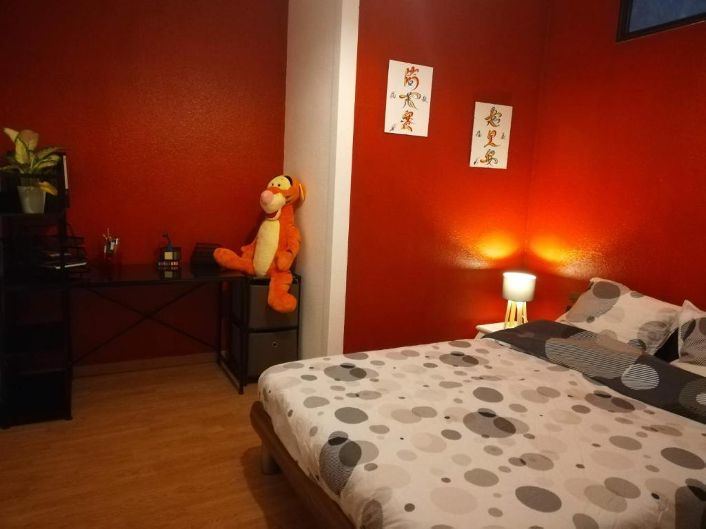 um quarto com uma cama com um bicho de peluche na parede em Appartement La Bernardine au coeur du Jura em Orgelet