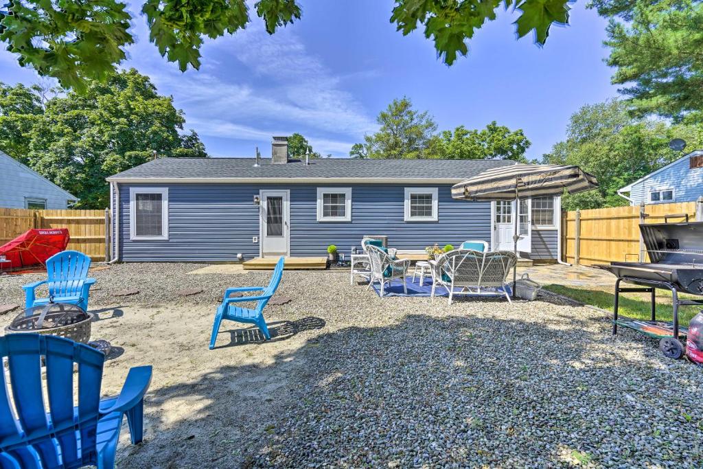 a yard with blue chairs and a house at Bayville Getaway with Fire Pit - 2 Mi to Beach! in Bayville