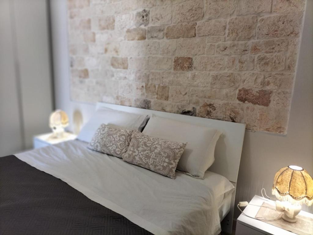1 dormitorio con cama blanca y pared de ladrillo en Casetta Angelini, en Locorotondo