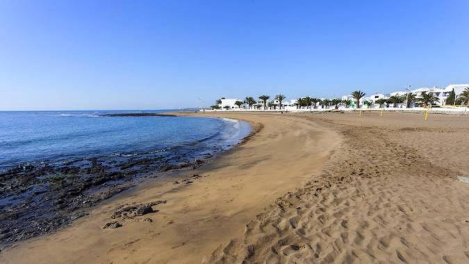 una spiaggia con impronte di piedi nella sabbia e nell'oceano di Apartamento Remo a Playa Honda