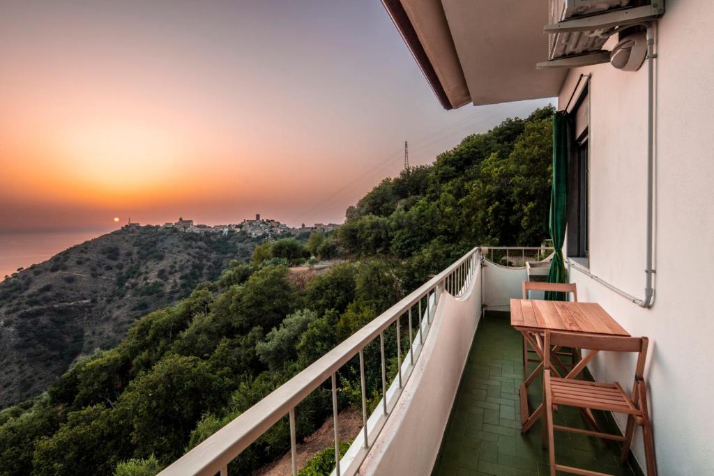 balcón con mesa y vistas al océano en La Valle di Hermes en Piraino