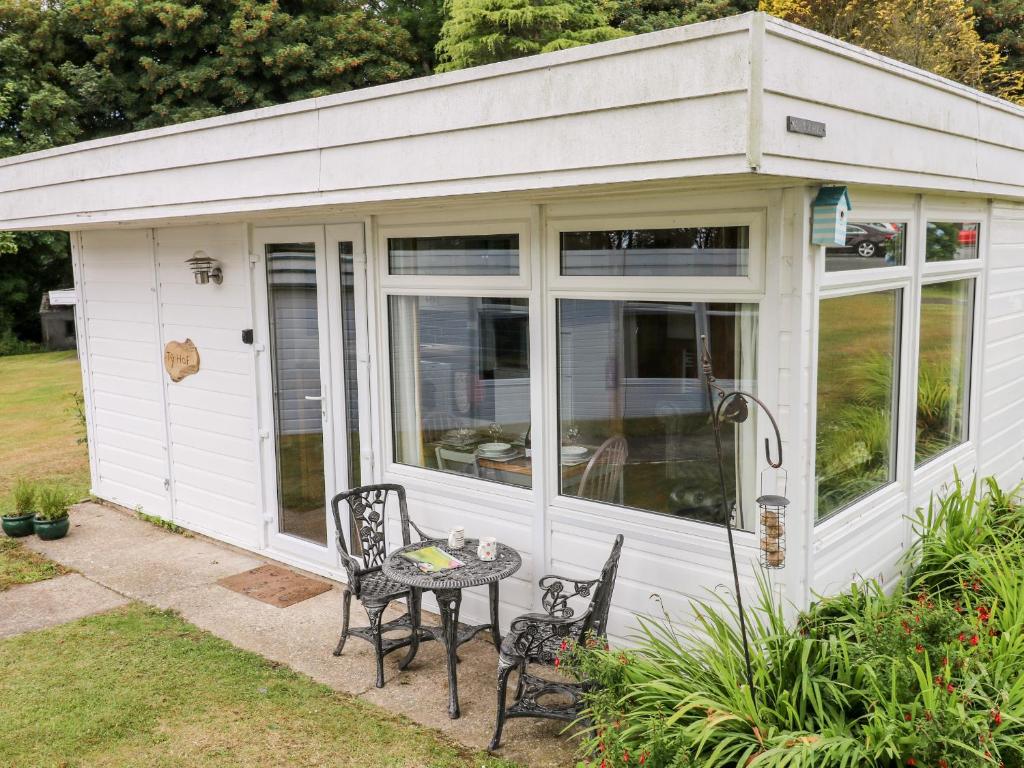 a white shed with a table and chairs in a yard at Ty Haf in Haverfordwest