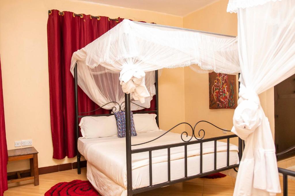 a bedroom with a canopy bed with red curtains at Klub Afriko Hotel Arusha in Arusha