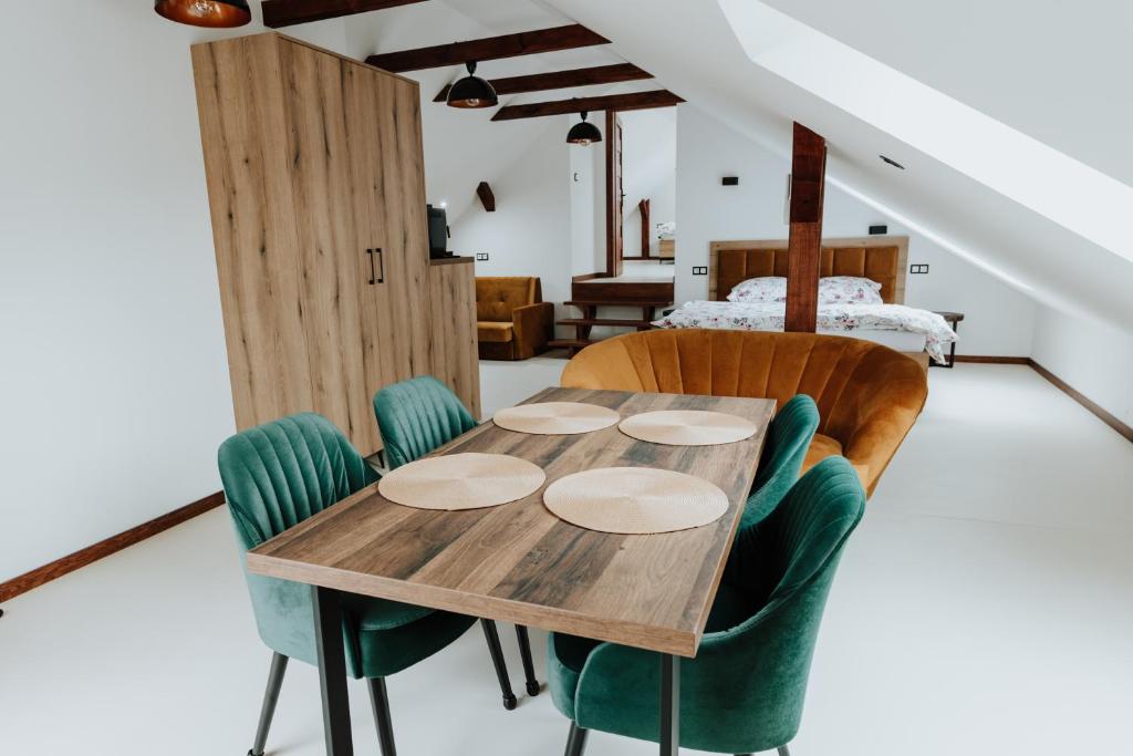 een houten tafel en stoelen in een kamer met een bed bij Skava Apartments Zator Energylandia in Wadowice