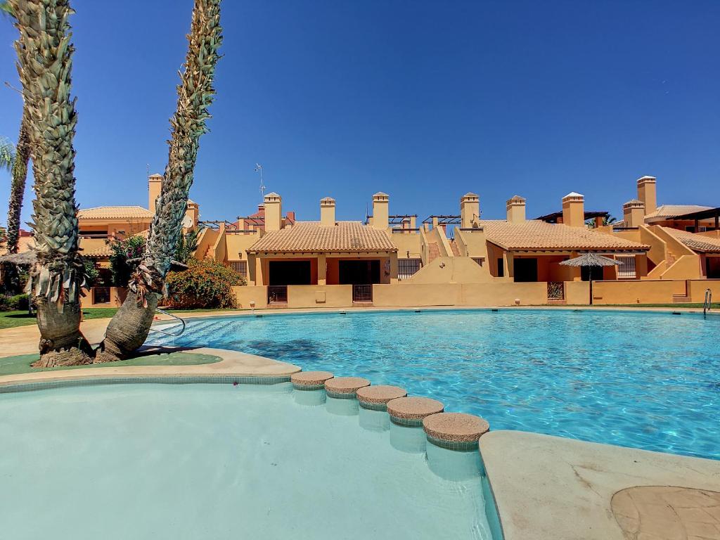 a large swimming pool with palm trees and a building at Albatros Playa 3 - 2507 in Mar de Cristal