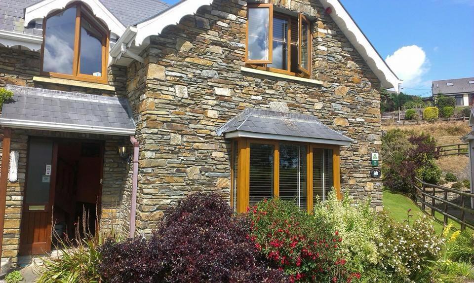 ein Steinhaus mit Fenstern und Blumen davor in der Unterkunft Ethan House B&B in Rosscarbery