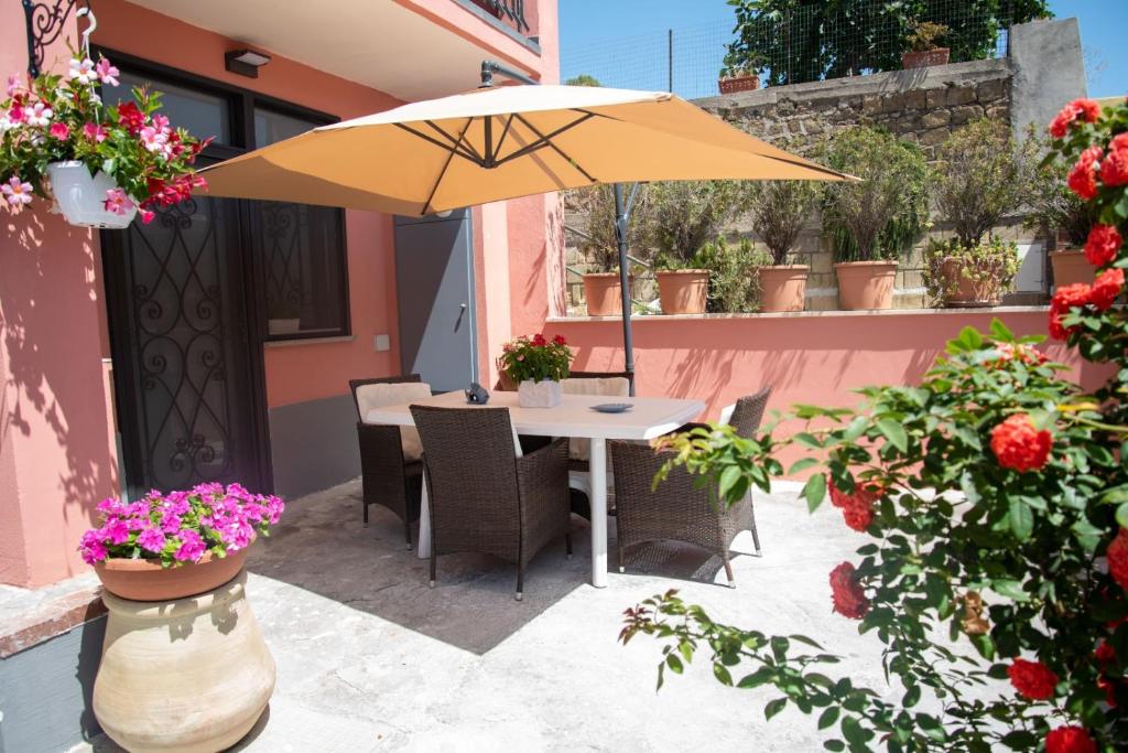 a table with an umbrella on a patio with flowers at ACQUAMARINA APPARTAMENT in Procida