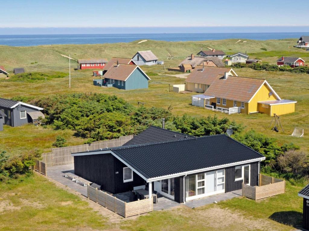 eine Gruppe von Häusern auf einem Feld neben dem Meer in der Unterkunft 10 person holiday home in Harbo re in Harboør