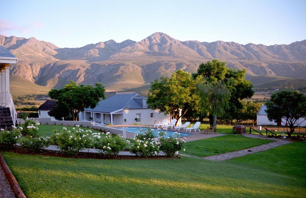 einen Blick auf ein Haus mit Bergen im Hintergrund in der Unterkunft Swartberg Country Manor in Matjiesrivier