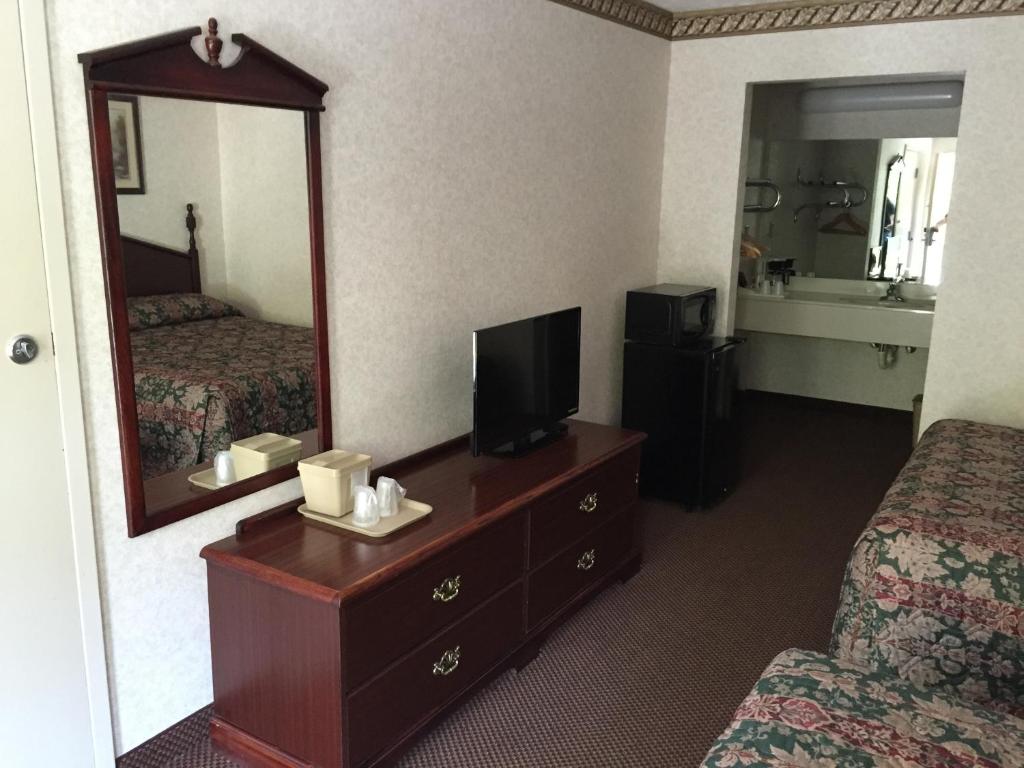 a hotel room with a bed and a mirror at Deerfield Inn in Somerville