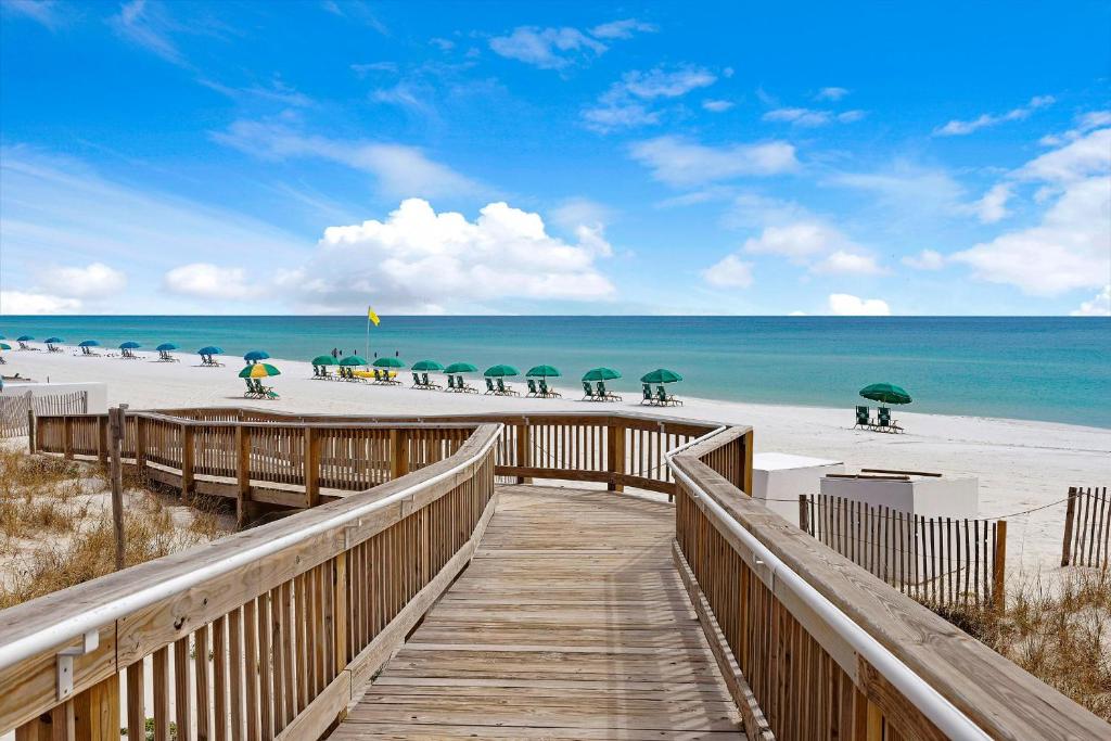 a wooden boardwalk leading to the beach with umbrellas at The Islander 416 in Destin