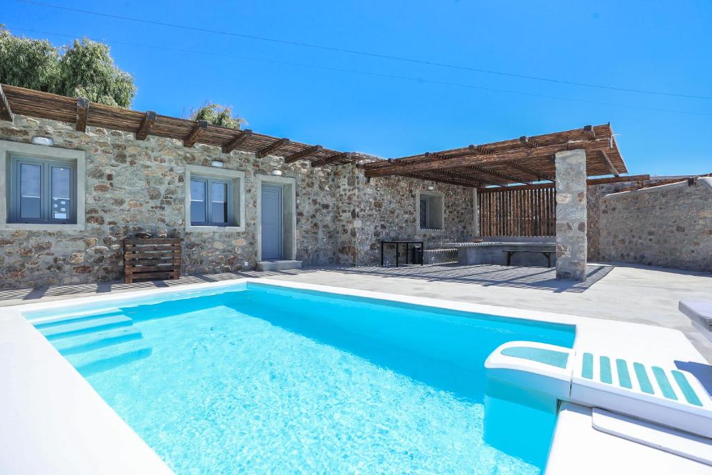 a swimming pool in front of a stone house at The George Villas Mykonos with Private Pool & Town Proximity in Mýkonos City