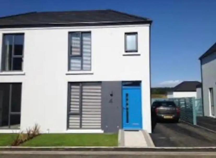 een wit huis met een blauwe deur en een auto bij Fabulous Portstewart Modern Seaside House NITB in Portstewart