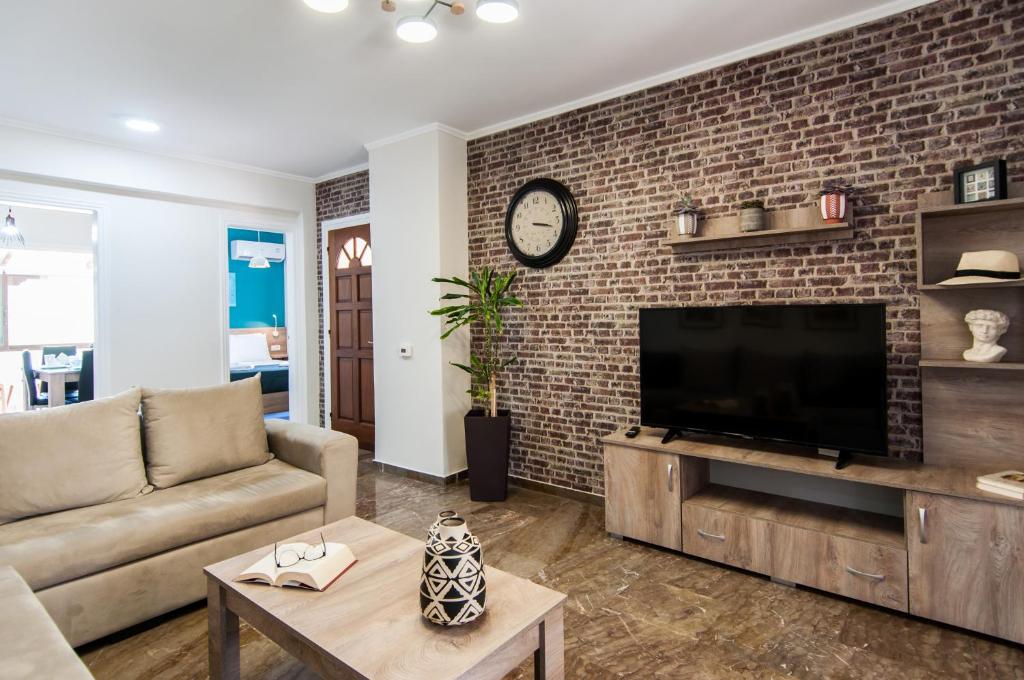 a living room with a tv and a brick wall at Magnolia Chic Apartment! in Zakynthos Town