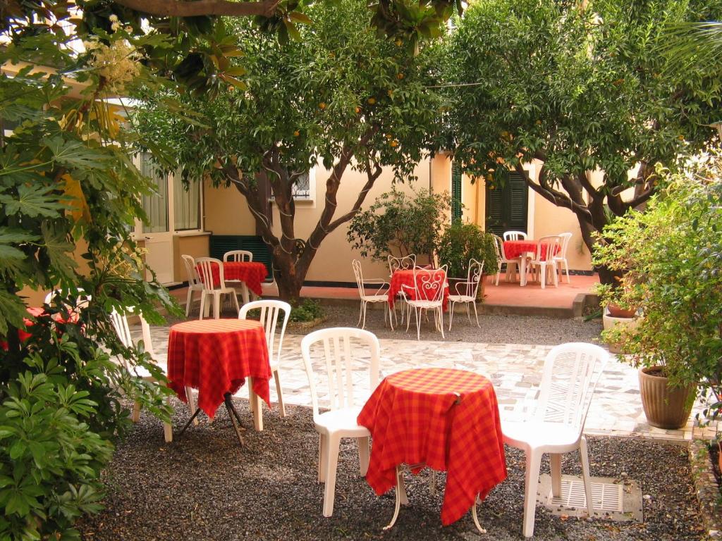 eine Terrasse mit Tischen und Stühlen sowie roten und weißen Decken in der Unterkunft Residence Italia in Finale Ligure