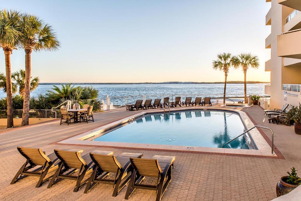 a swimming pool with chairs and a view of the ocean at East Pass 207 in Destin