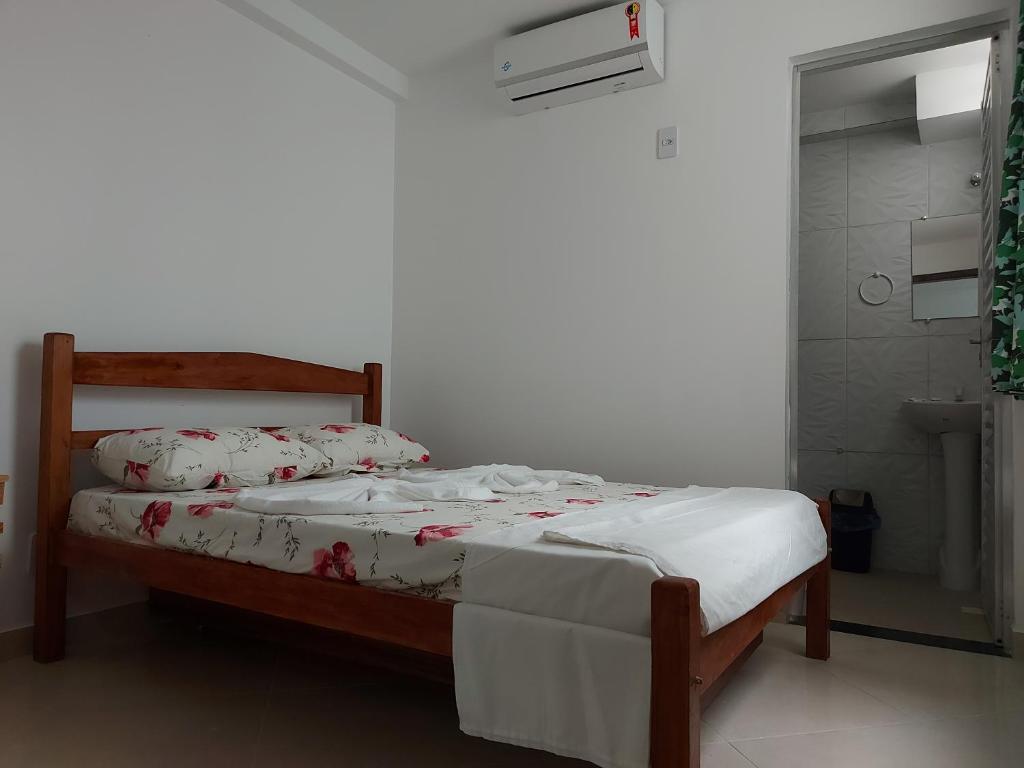 1 dormitorio con 1 cama con sábanas blancas y flores rojas en Casarão Nazaré Hostel, en Salvador