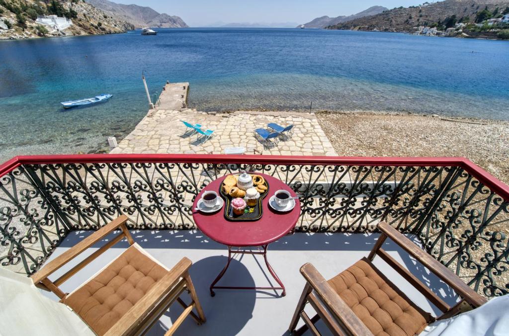 a table and chairs on a balcony with a view of the water at Petridi House in Symi