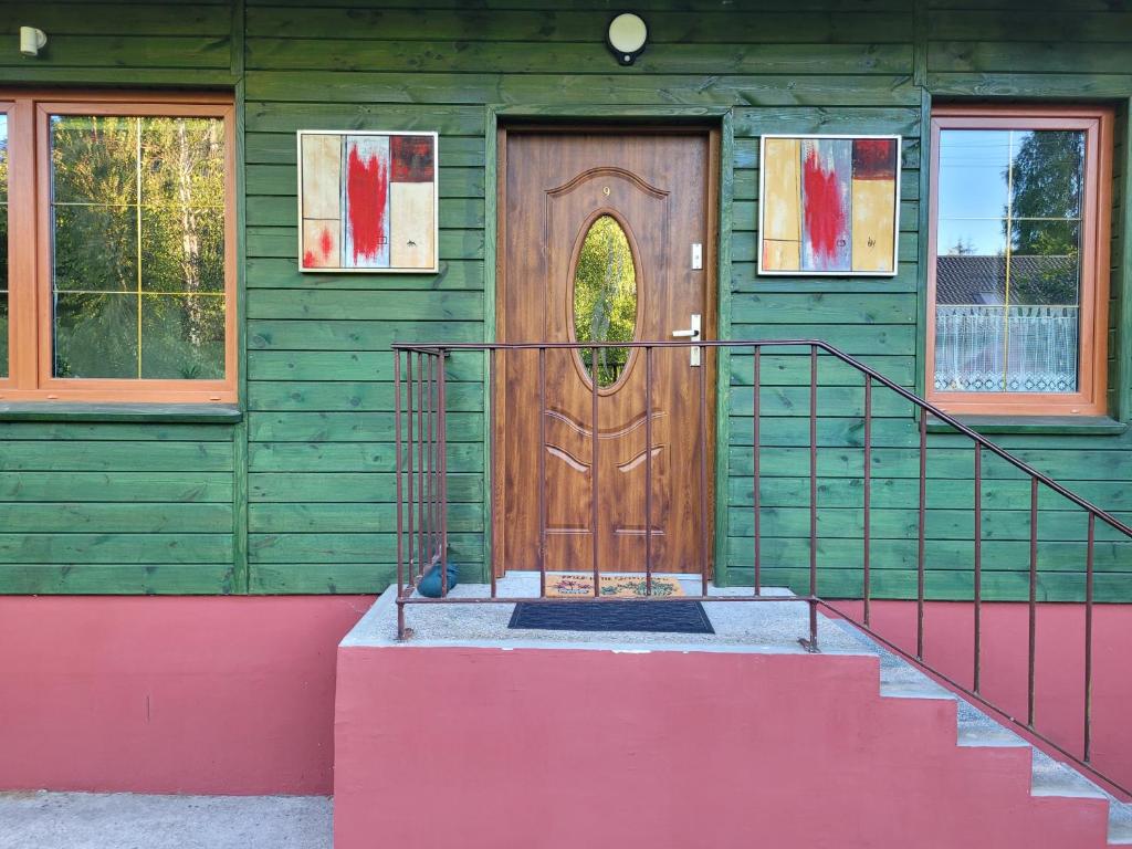 Casa verde con puerta de madera y escalera en Zielony Domek - Tleń Bory Tucholskie en Tleń