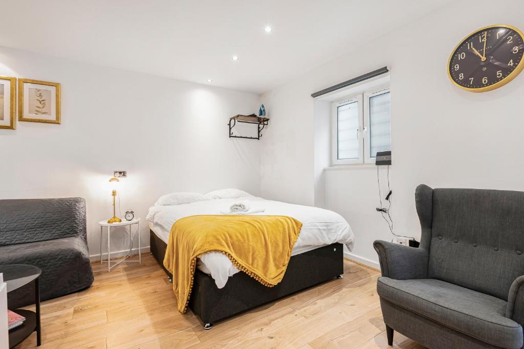 ロンドンにあるBeautiful Hyde Park Studio Flatのベッドルーム1室(ベッド1台、椅子、時計付)
