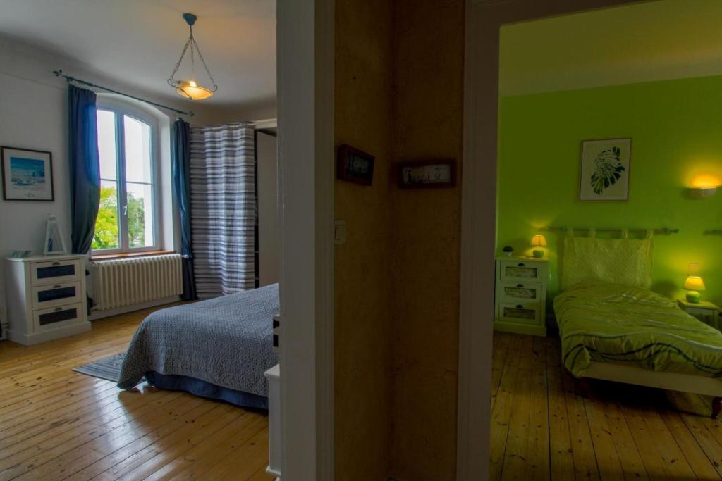 um quarto com paredes verdes, uma cama e uma janela em Le Logis du Canal em Marennes