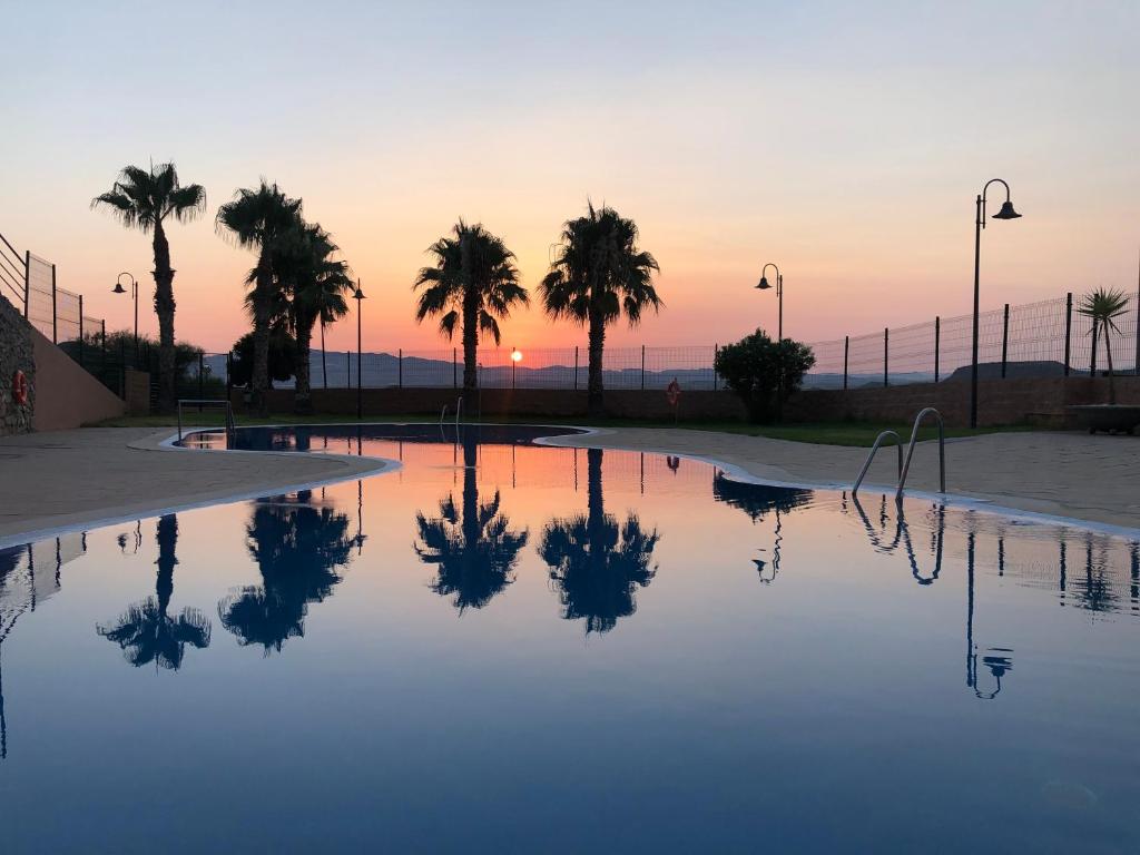 basen z palmami i zachodem słońca w obiekcie Mojacar terrazas del Golf w mieście Mojácar
