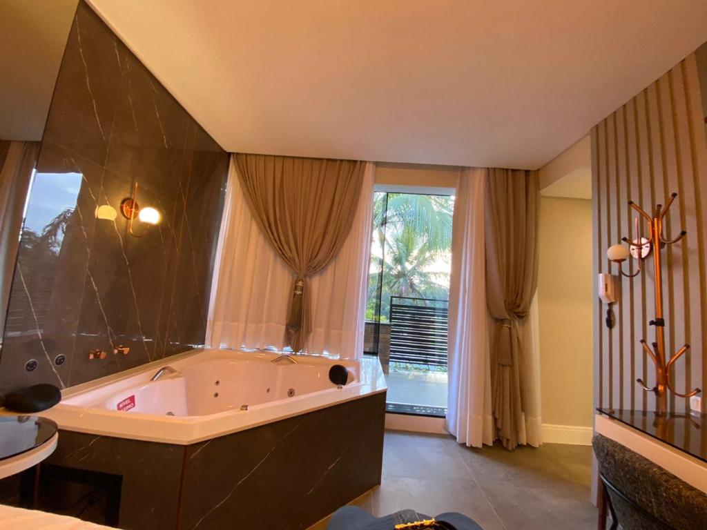 uma grande casa de banho com banheira e uma grande janela em Pousada Bella Casa em Balneário Camboriú