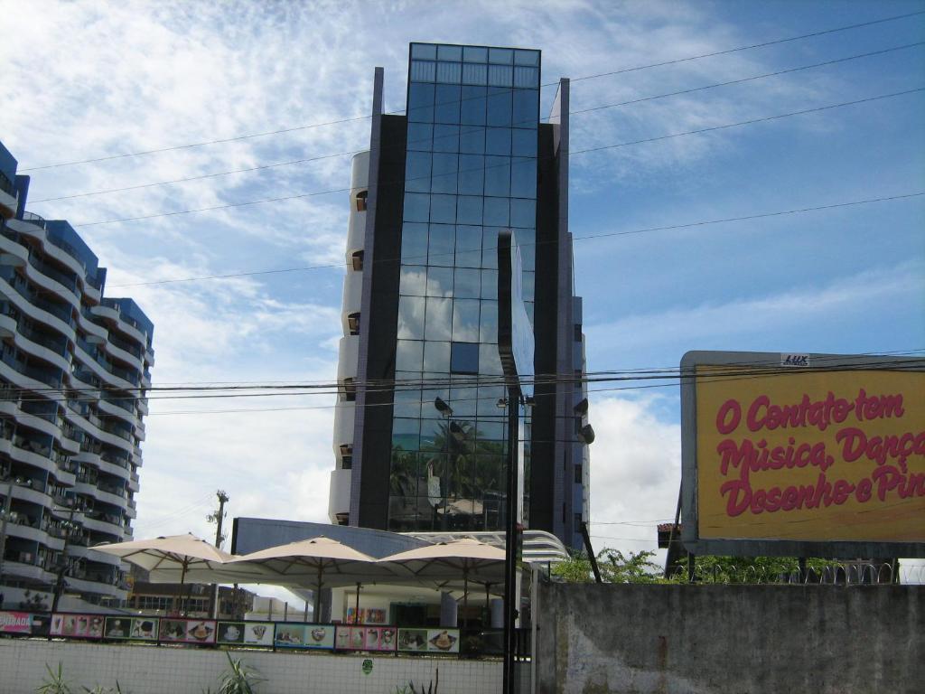 un gran edificio de cristal con un cartel delante en Apartamentos Praia de Pajucara, en Maceió