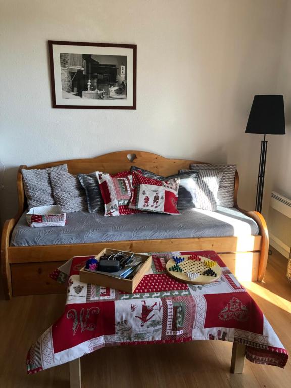 a bed with red and white pillows on it at SUPER BESSE Appartement LE GÎTE BESSARD 6 couchages Le Bois de la Reine in Besse-et-Saint-Anastaise