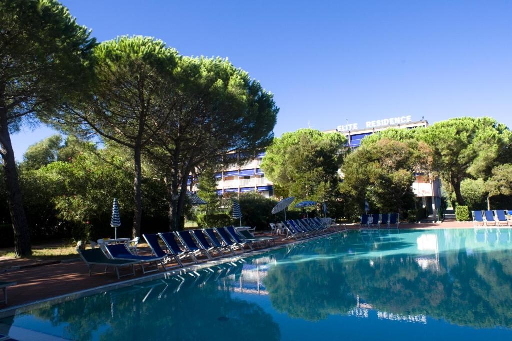 una piscina con sillas y árboles y un edificio en Residence Elite, en Marina di Campo