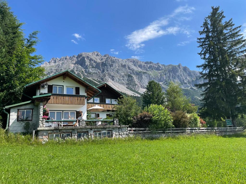 una casa en un campo con una montaña en el fondo en Ferienhaus Korda, en Ramsau am Dachstein