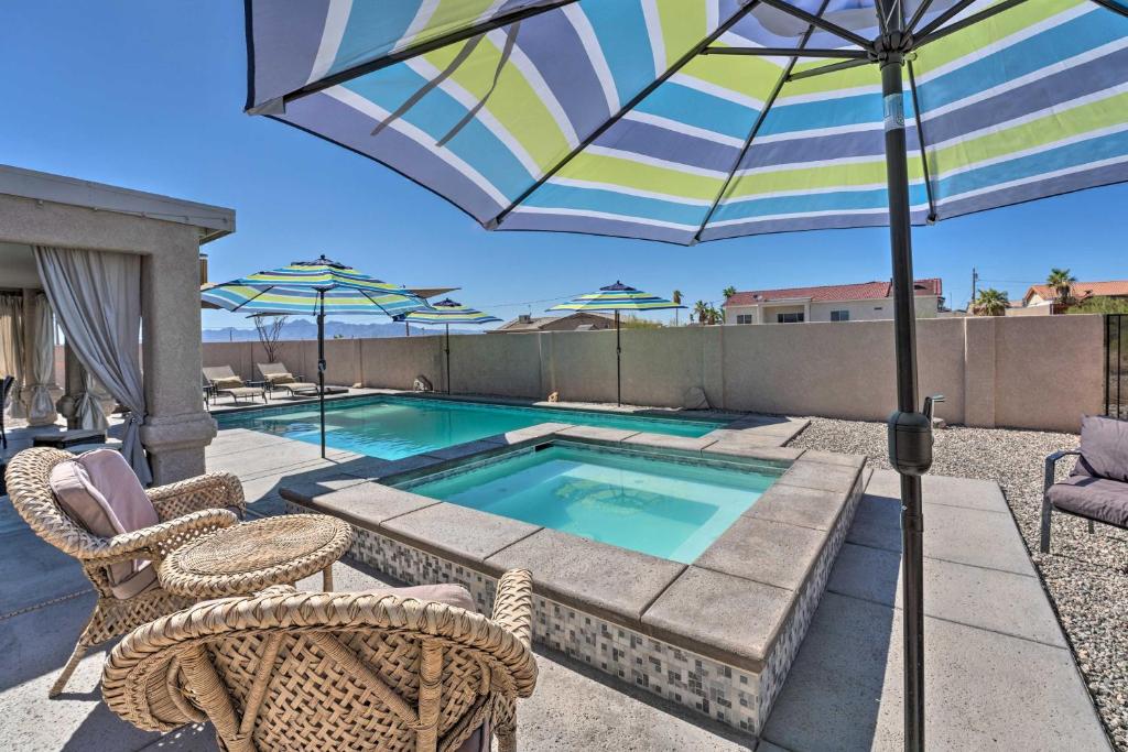 a patio with a pool and an umbrella and chairs at Central Lake Havasu City House Grill and EV Charger in Lake Havasu City
