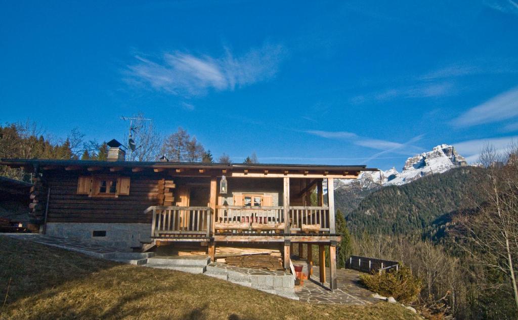 a log cabin with a porch and a mountain at Chalet Bait del Papi in Madonna di Campiglio