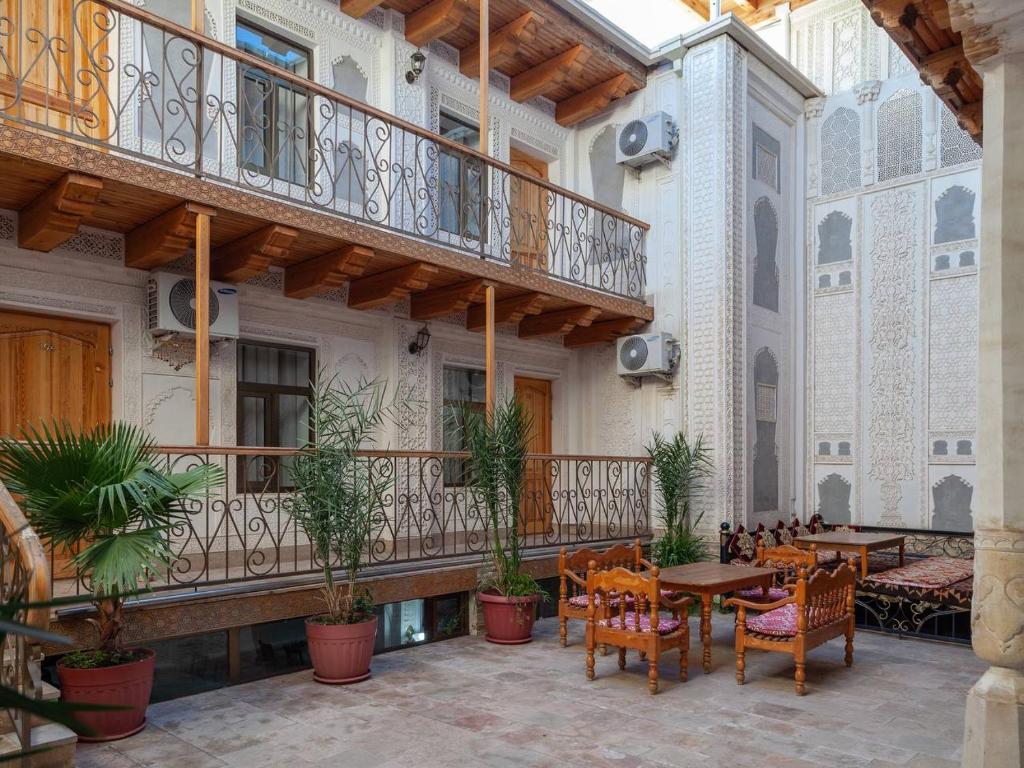 a patio with tables and chairs and a balcony at Porso Boutique Hotel in Bukhara