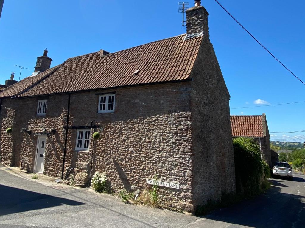 an old stone house on the side of a street at The Nook- A Rustic Cottage in a Beautiful Village. in Draycott