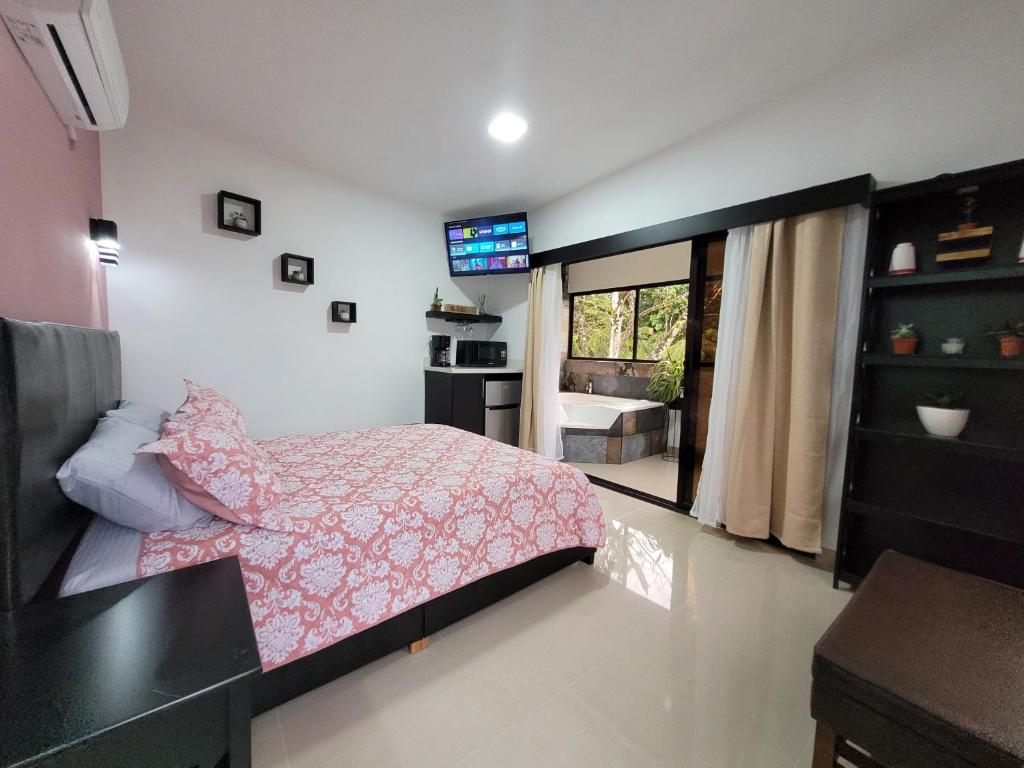a bedroom with a pink bed and a kitchen at Loky's Apartments La Fortuna in Fortuna