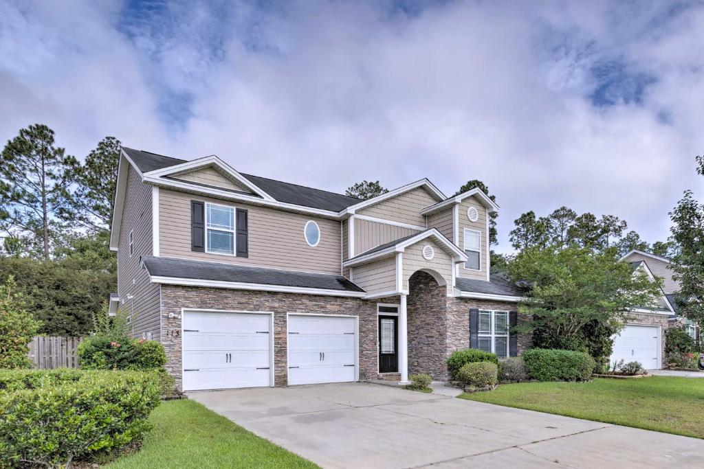 a house with two garage doors in a yard at Spacious Pooler Home with Family-Friendly Perks in Savannah