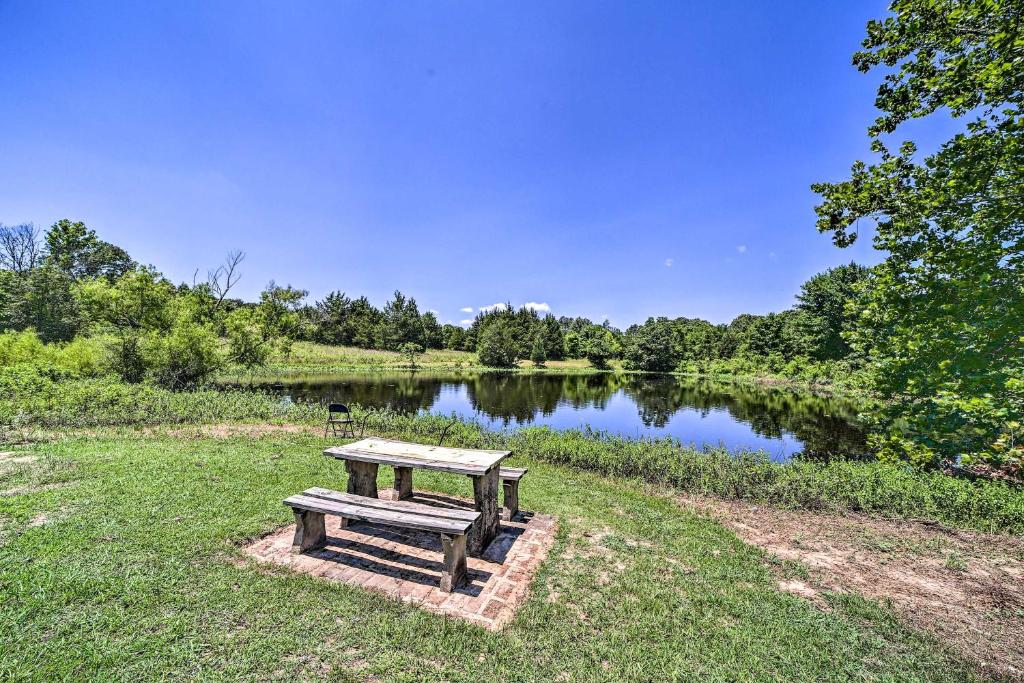 a picnic table in the grass next to a lake at Stunning Oklahoma Home about 3 Mi to Spiro Mounds in Pocola