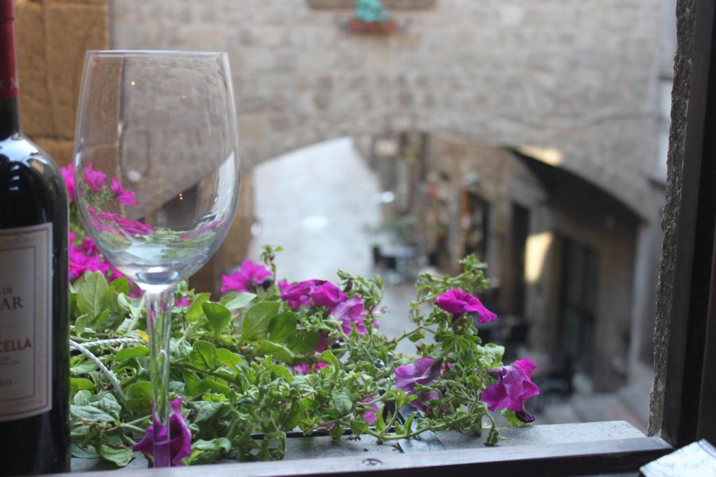 een wijnglas op een vensterbank met paarse bloemen bij aCasetta GuestHouse in Viterbo