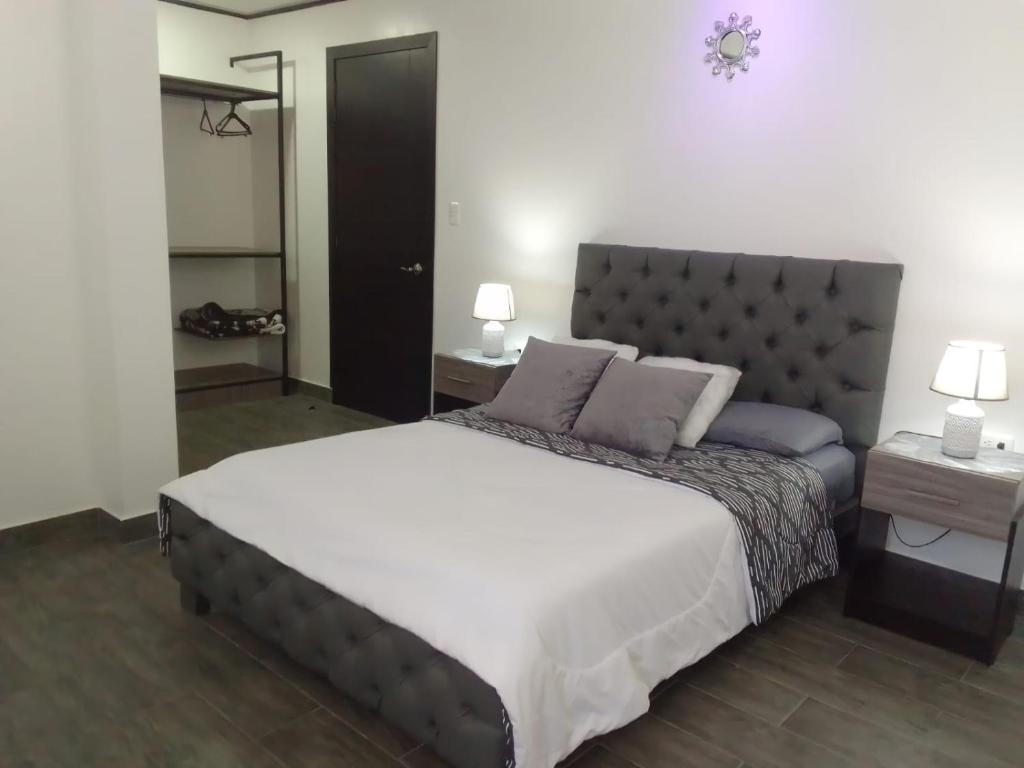 een slaapkamer met een groot bed met 2 tafels en 2 lampen bij Jardines Ambato in Ambato