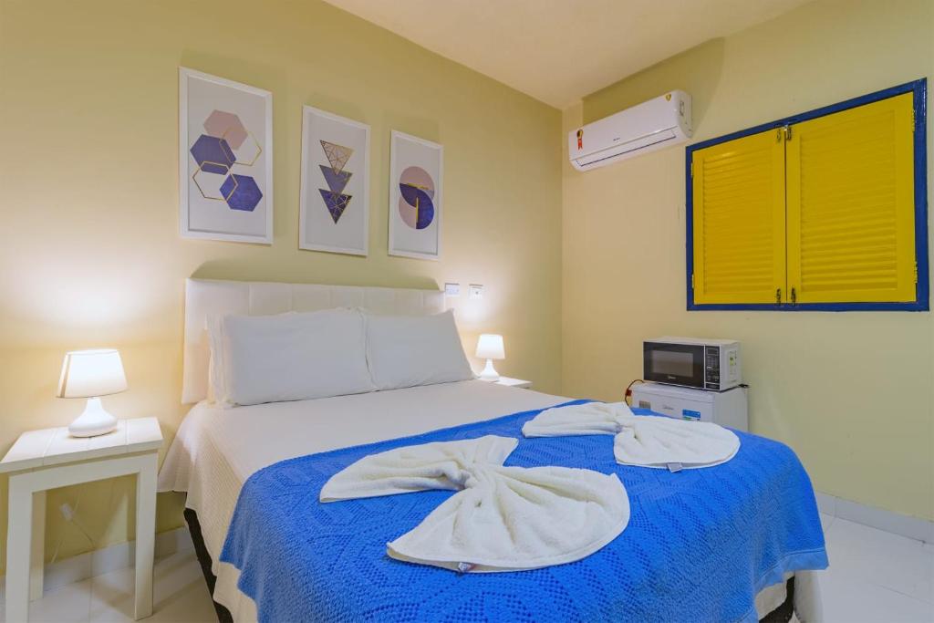um quarto com uma cama com um cobertor azul em Suítes B6 em Porto de Galinhas