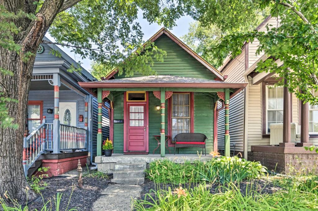 a green house with a pink door and a tree at Charming 1875 Indianapolis Home in Downtown! in Indianapolis