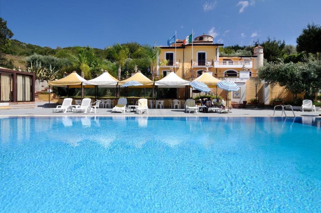 a large swimming pool with chairs and umbrellas at Hotel Villa La Colombaia in Agropoli
