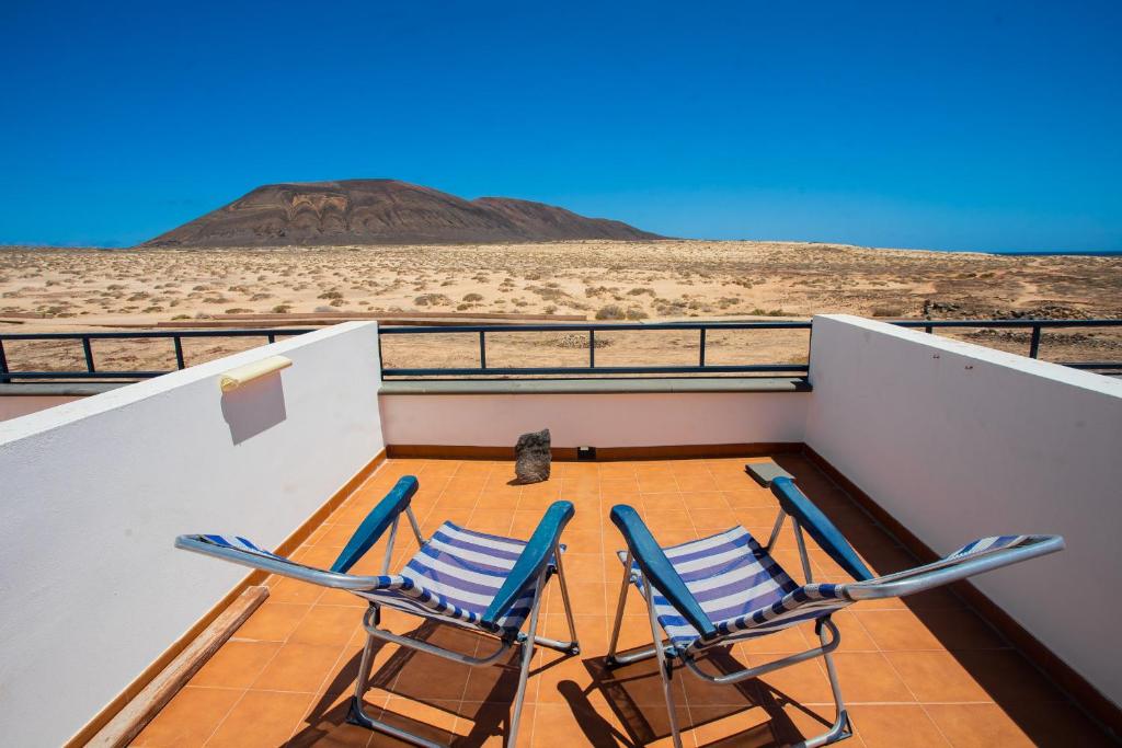 two chairs on a balcony with a view of the desert at Eslanzarote La Duna House, Wifi, Sea views in Caleta de Sebo