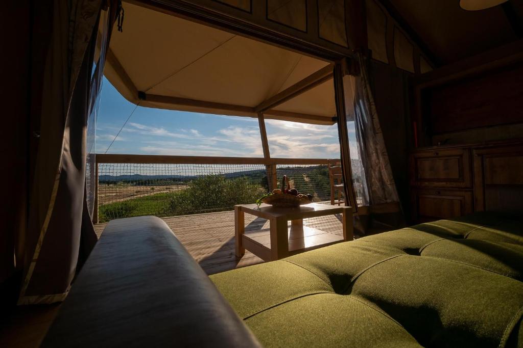a room with a bed and a table with a large window at Glamping Podere San Jacopo in Massa Marittima