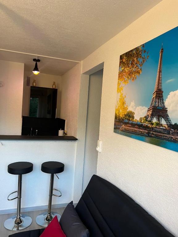 a living room with a couch and a picture of the eiffel tower at Cocon Accès facile Parking Gratuit in Belfort