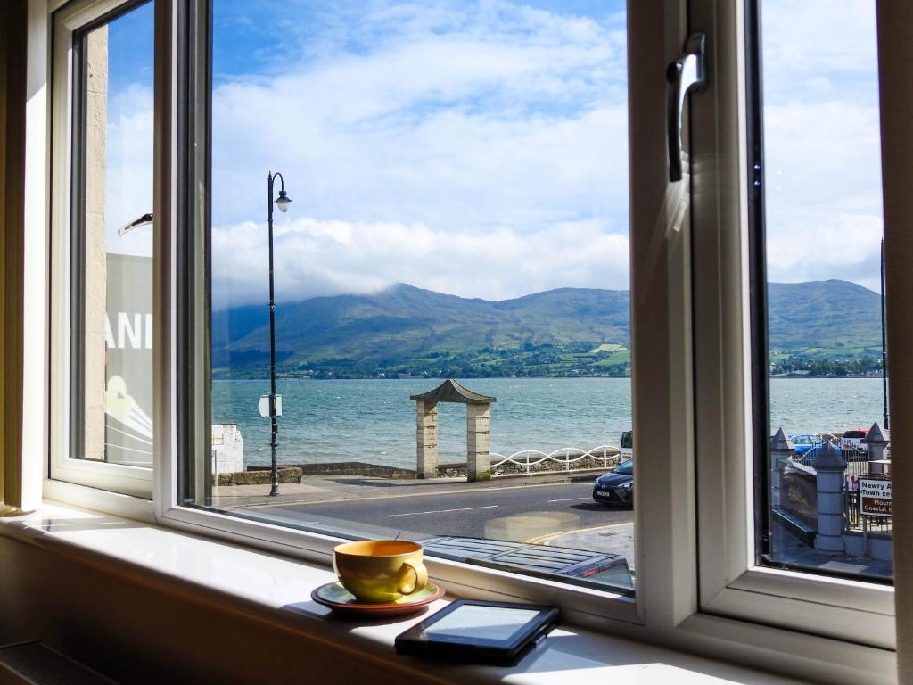 a window with a cup and a book on a window sill at Lough Álainn - Tourism NI Certified in Warrenpoint